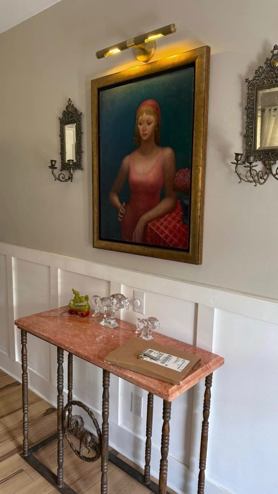 Picture light illuminating a framed painting in a hallway