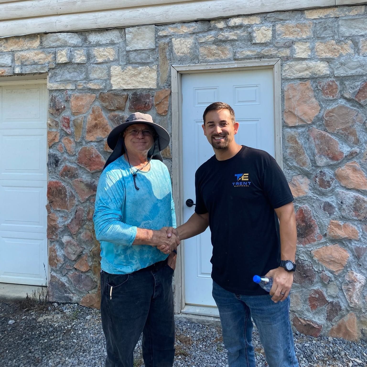 Ryan Trent shaking hands with a customer outside a stone home