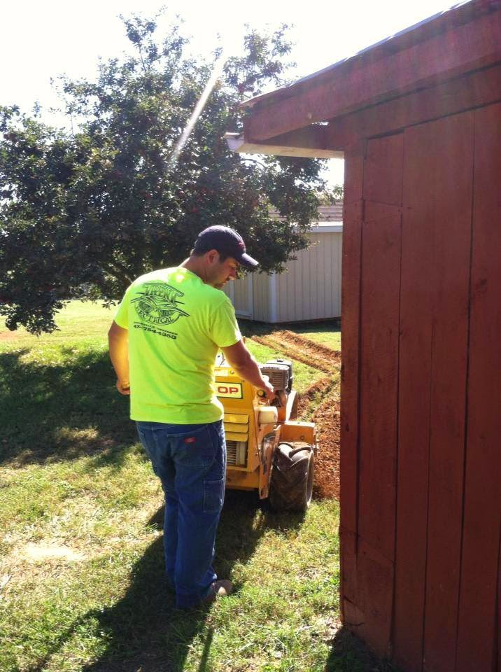 Walk-behind trencher cutting a shallow electrical trench across a residential yard in East Tennessee