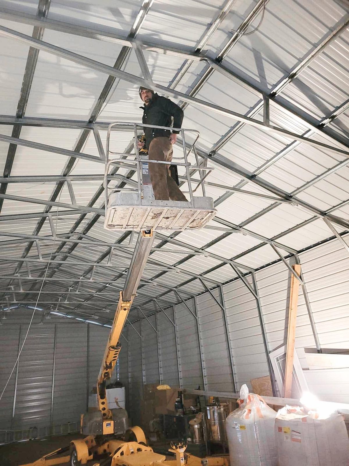 Electrician working from a boom lift inside a large metal commercial structure