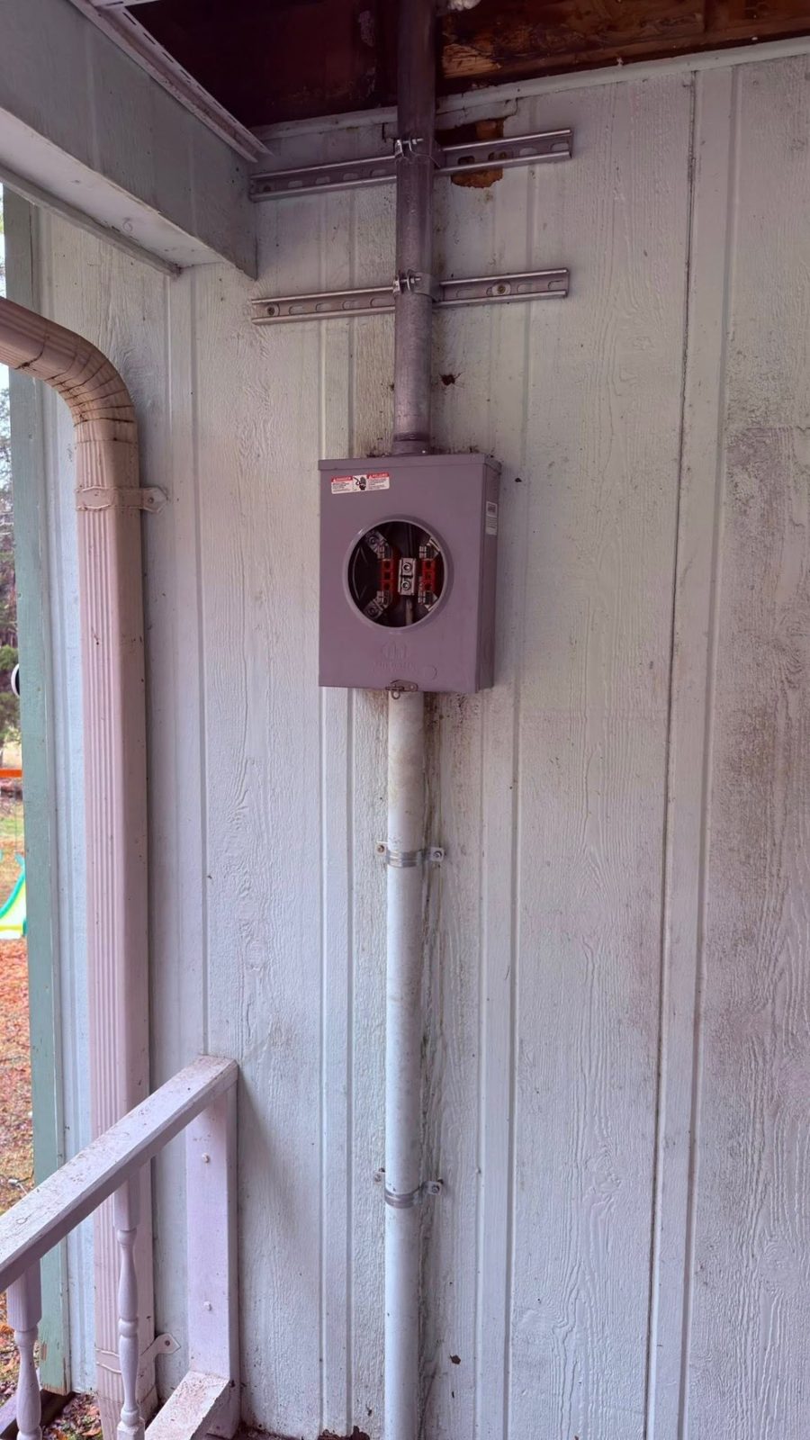 New meter base installed on white siding with conduit routed through a porch ceiling in Rogersville TN