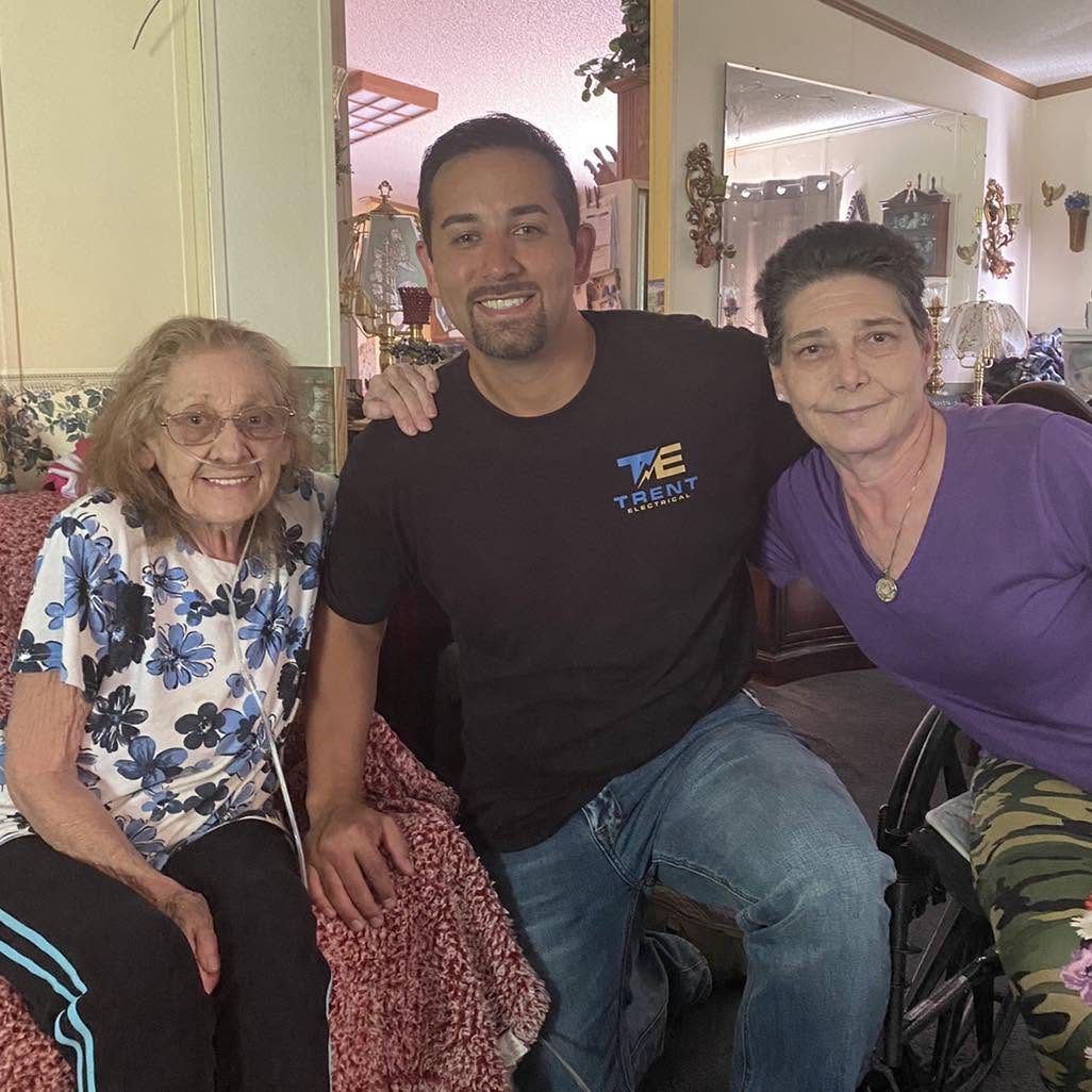 Ryan Trent with two happy customers after finishing electrical work in their home