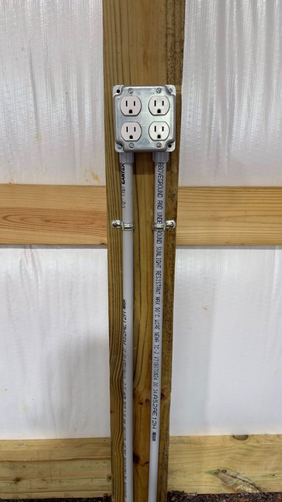 Four-plex outlet mounted on a wood post with PVC conduit in a pole barn