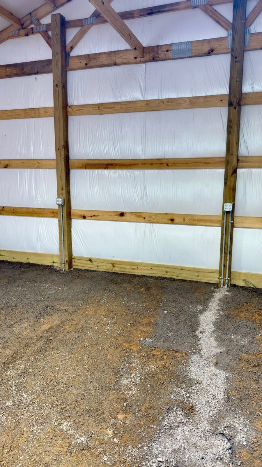 Surface-mounted conduit and boxes run along exposed wood framing in a barn
