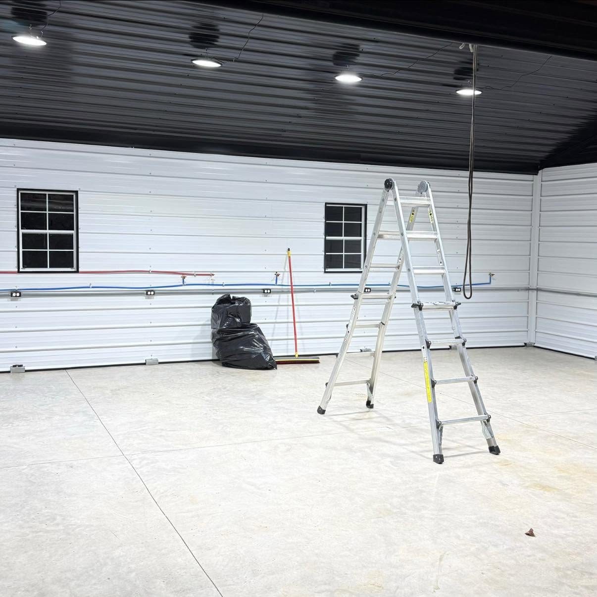 High-bay lighting and surface conduit inside a commercial metal building