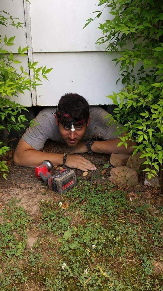 Electrician with a headlamp entering a tight crawlspace to trace a residential wiring fault