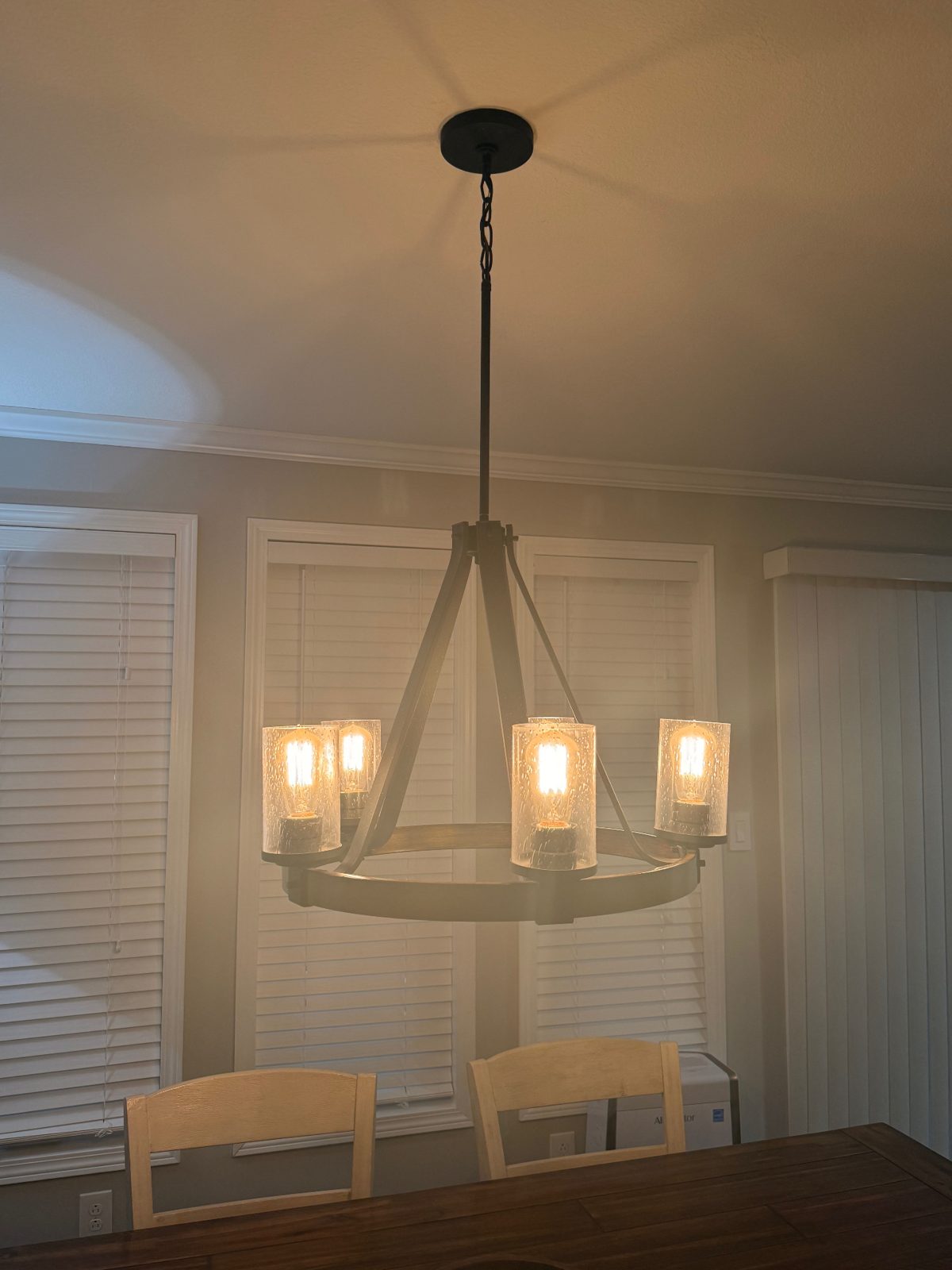 Wagon wheel chandelier with Edison bulbs hung in a dining room