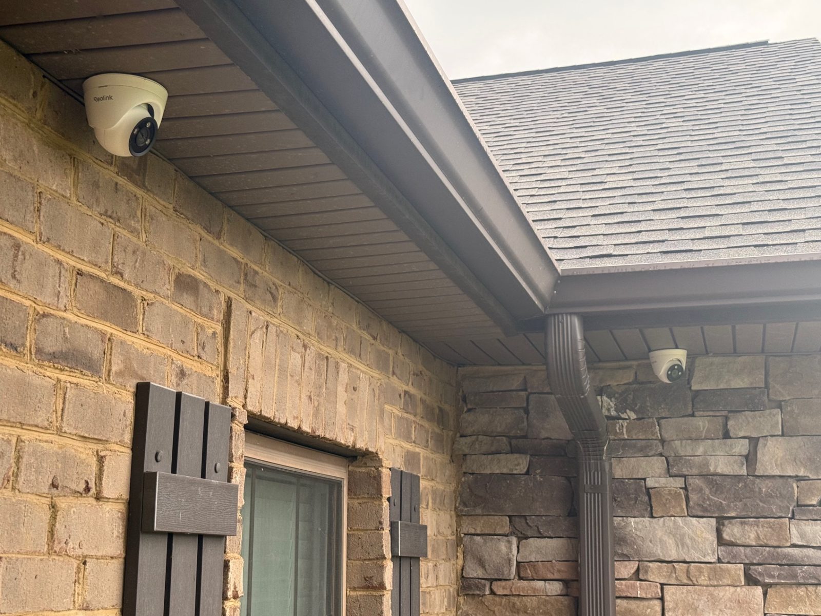 Two dome security cameras mounted under the soffit of a brick building