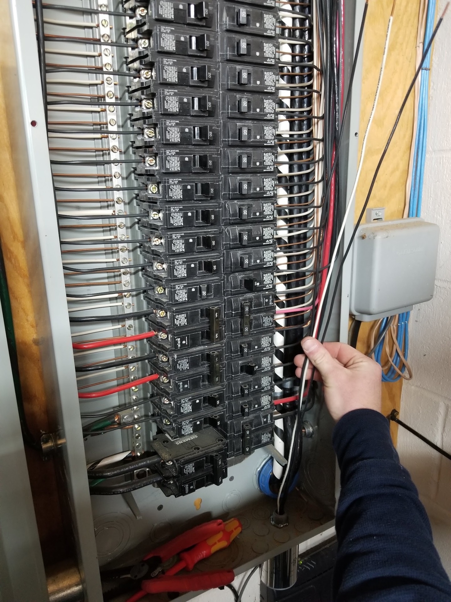 Electrician pointing out breaker and wiring detail inside an upgraded residential electrical panel