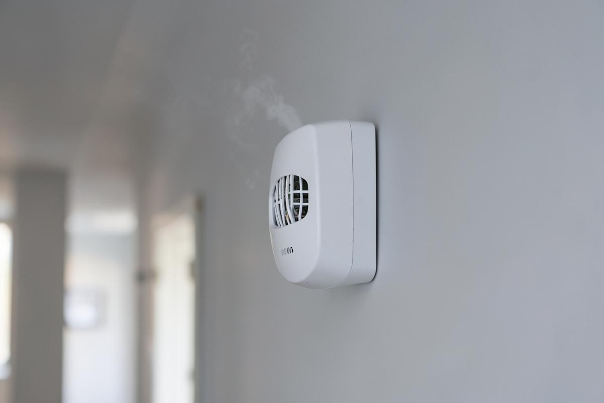 A modern smoke and carbon monoxide alarm mounted on a residential ceiling